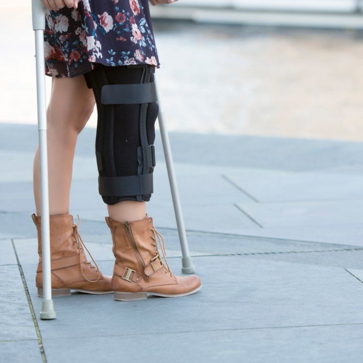 mujer con muletas y aparato inmobilizador en la pierna